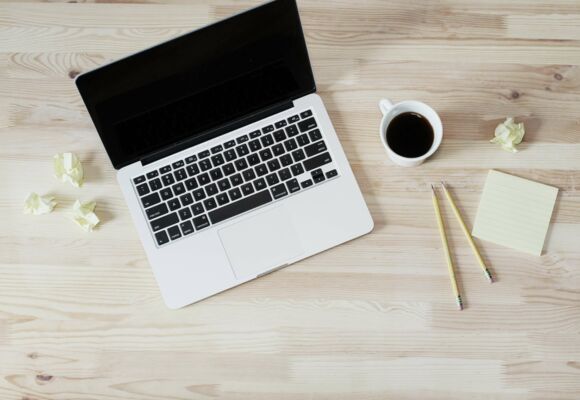 Recruiting-Strategie: was Arbeitgeber anziehend macht. Laptop mit Kaffeetasse und Arbeitsutensilien auf Schreibtisch