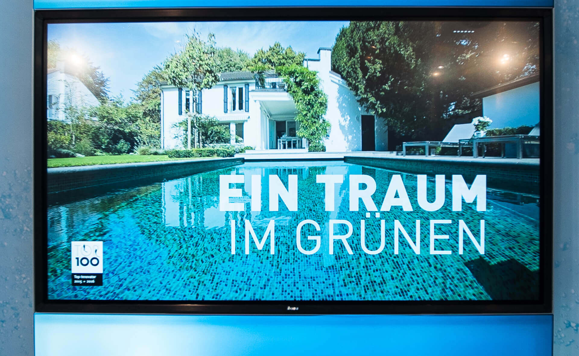 Ospa Messedesign: Screen mit Pool-Bild und Aufschrift "Ein Traum im Grünen"